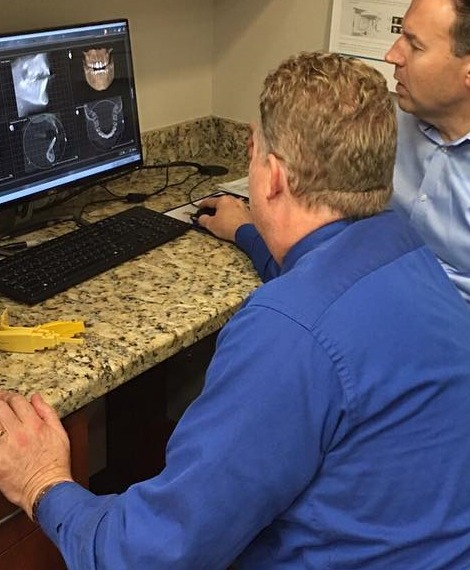 Dentist and dental team member reviewing digital dental x rays
