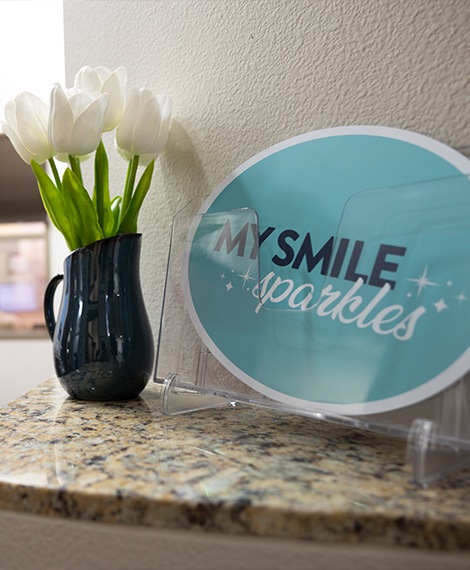 My smile sparkles sign on desk next to vase with white tulips