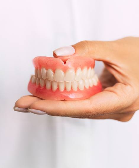 Dentist holding a set of traditional full dentures in Henderson