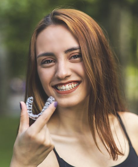 Woman holding Clear Correct aligner outdoors