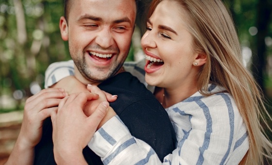Young man and woman laughing together outdoors