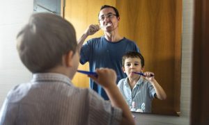 Father and son brushing while away from dentist in Henderson.