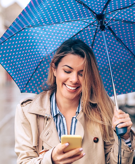 Woman under an umbrella looking at her phone
