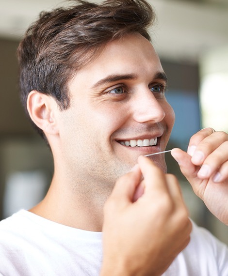 Man flossing teeth to maintain oral health at home