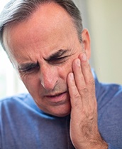Man with lost dental crown holding cheek