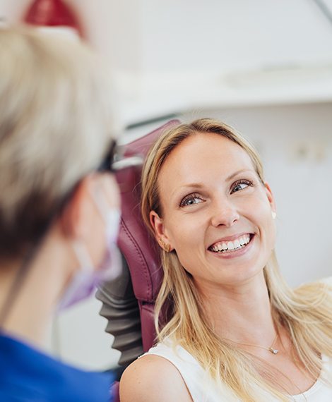 Woman smiling at dental team during exam to prevent dental emergencies
