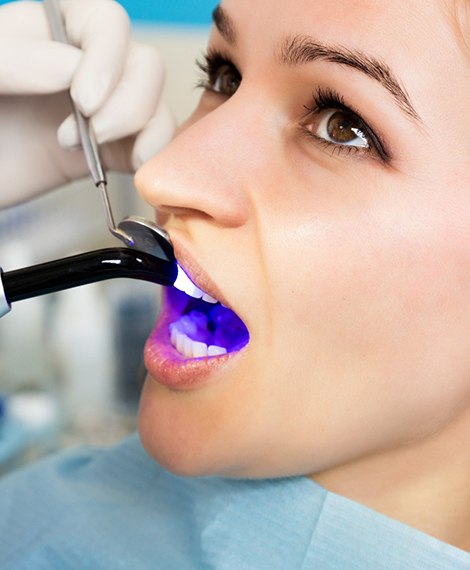 UV light applied to woman’s dental treatment