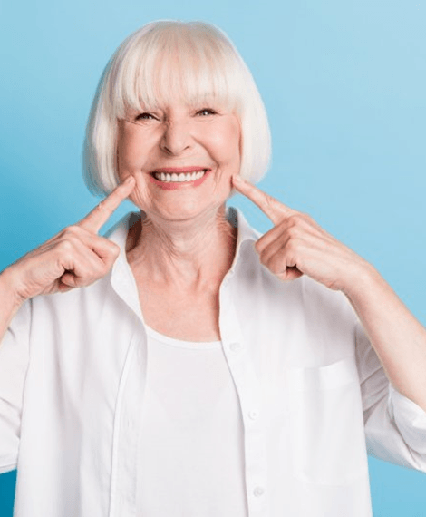 a woman smiling and pointing at her full arch replacements