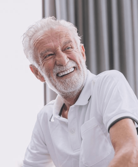 A man smiling after receiving implant dentures