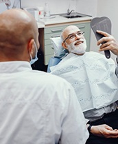 man beaming at his reflection after getting dental implants