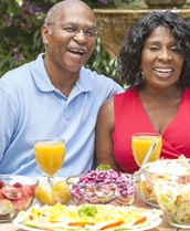 couple sitting outside at a table with various foods and drinks