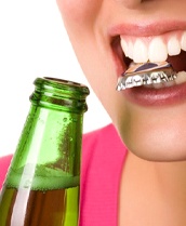 person opening a bottle with their teeth