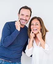 man and woman pointing to their smiles