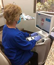dentist looking at a digital image of a patient’s teeth on a computer
