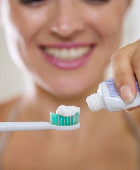 Woman putting toothpaste onto an electric toothbrush