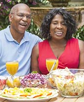 Senior couple sitting at a table with various foods and beverages