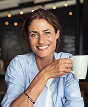 smiling woman holding a white coffee mug