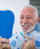 senior man admiring his new smile with dental implants