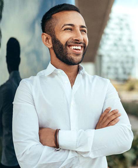 Man in a white collared shirt standing with his arms crossed