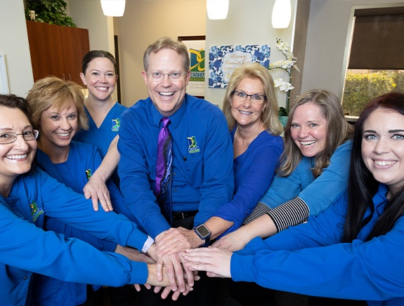 Doctor Noorda and dental team members putting their hands together