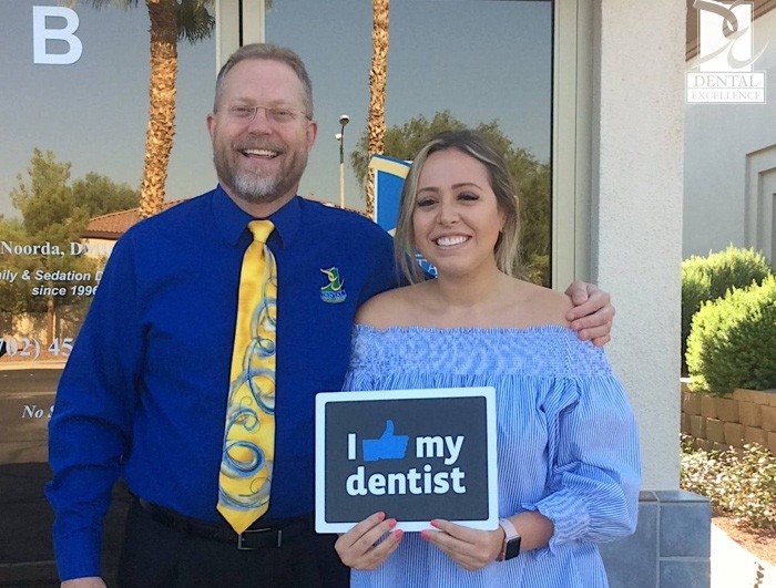 Doctor Noorda smiling with young woman outside of Henderson dental office