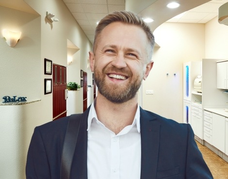 Man in dark blue jacket laughing in dental office