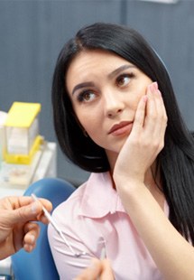 Woman with dental emergency holding her cheek in pain