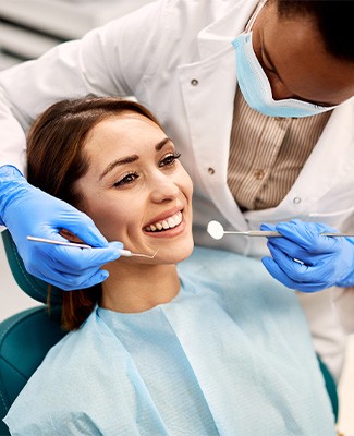 Woman about to undergo dental exam by dentist in blue gloves