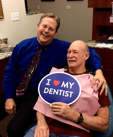 Dentist and patient smiling in dental exam room after dental hygiene visit
