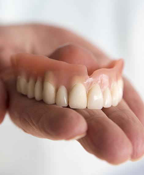 Hand holding a full denture