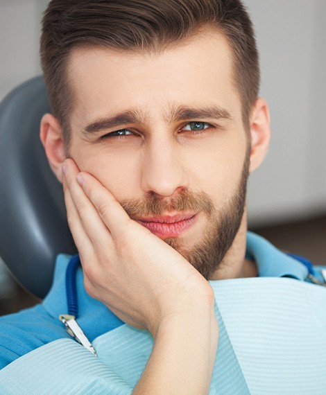 Male dental patient rubbing jaw due to tooth pain