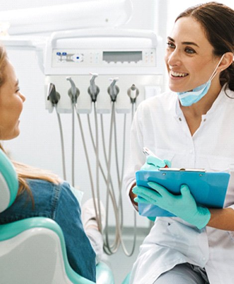 Dentist with clipboard smiling while talking to patient
