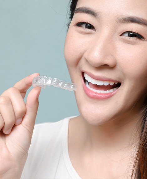 Smiling woman holding a Sure Smile aligner tray