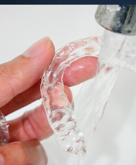 Person rinsing off a Sure Smile aligner tray