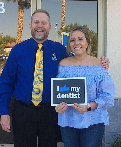 Dentist and patient smiling in front of dental office building