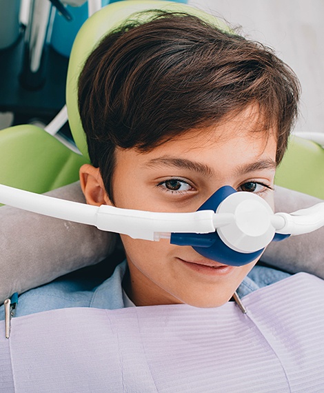 Young patient in dental chair with dental sedation mask in place