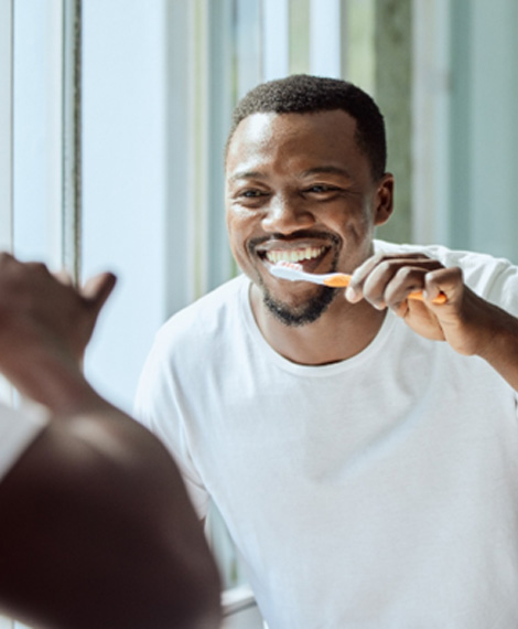 Man smiling while brushing his teeth