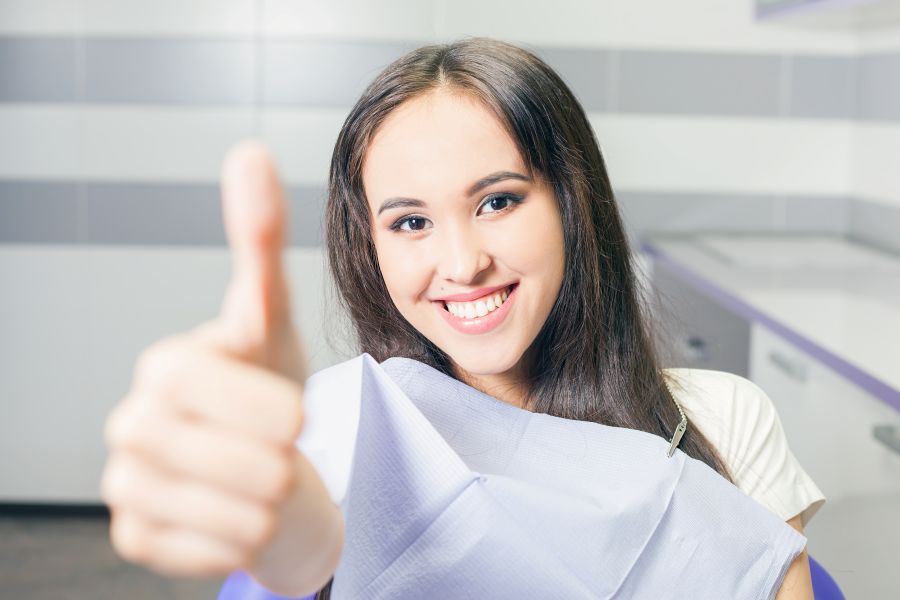 A woman giving the thumbs up sign at the dentist