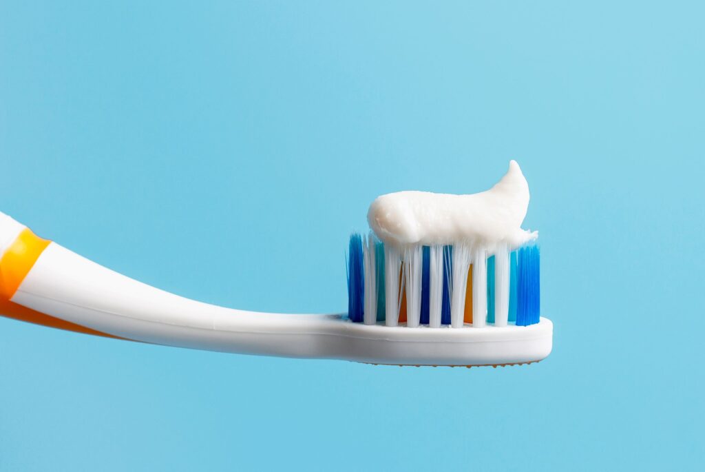 White toothpaste on standard toothbrush with blue background