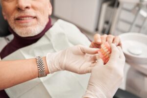 Man giving his dentures to his dentist
